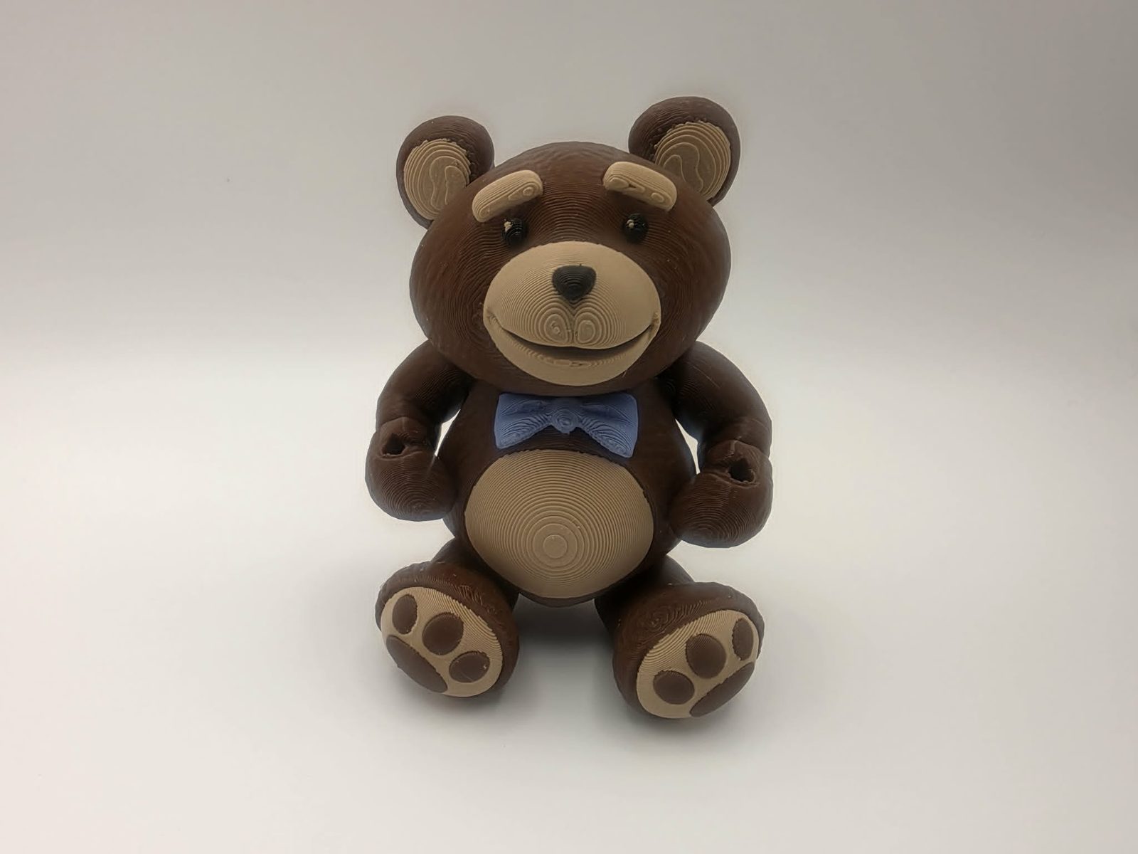Teddy Bear - Sir Snugglesworth - 3" Wide Outer Arm to Outer Arm x 1.4" Belly to Back x 4.25" Head to Feet - Chocolate, Matte Light Brown, Black, Blue and White 3D printed item imag