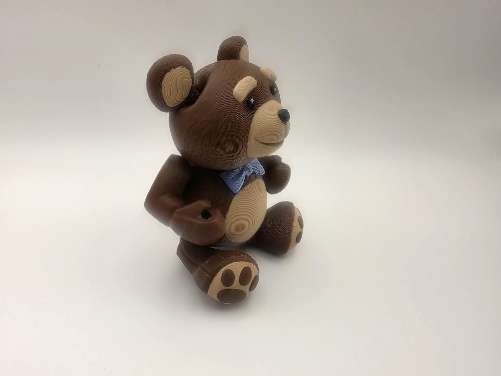 Teddy Bear - Sir Snugglesworth - 3" Wide Outer Arm to Outer Arm x 1.4" Belly to Back x 4.25" Head to Feet - Chocolate, Matte Light Brown, Black, Blue and White 3D printed item imag